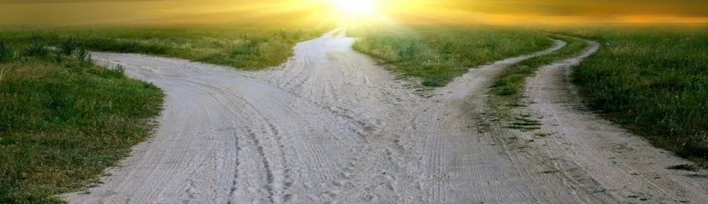 A dirt track splitting into three roads at sunset.